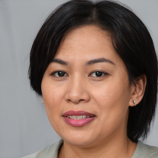 Joyful asian adult female with medium  brown hair and brown eyes