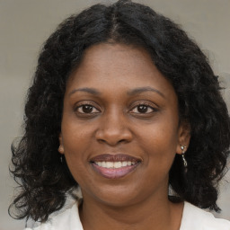 Joyful black young-adult female with long  brown hair and brown eyes