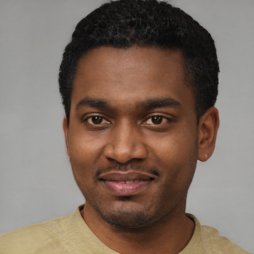 Joyful black young-adult male with short  black hair and brown eyes