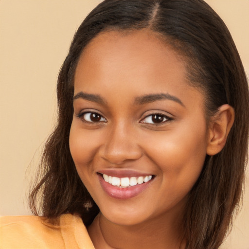 Joyful black young-adult female with long  brown hair and brown eyes