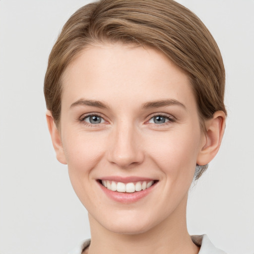 Joyful white young-adult female with short  brown hair and grey eyes