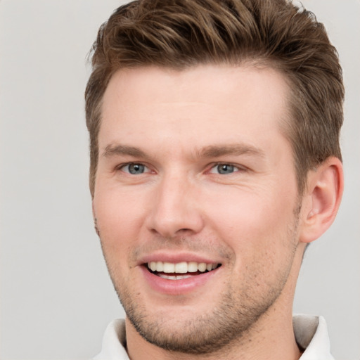 Joyful white young-adult male with short  brown hair and grey eyes