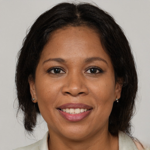Joyful black adult female with medium  brown hair and brown eyes