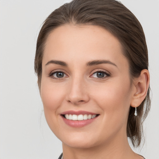 Joyful white young-adult female with medium  brown hair and grey eyes