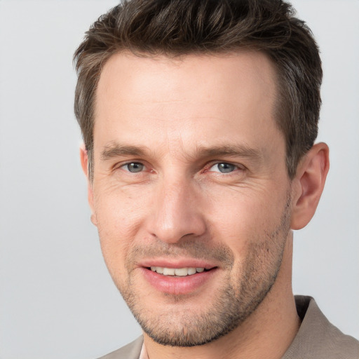 Joyful white adult male with short  brown hair and grey eyes