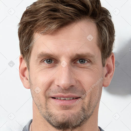 Joyful white young-adult male with short  brown hair and grey eyes