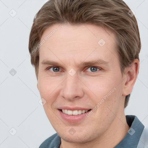 Joyful white young-adult male with short  brown hair and grey eyes