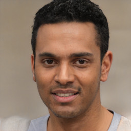 Joyful latino young-adult male with short  black hair and brown eyes