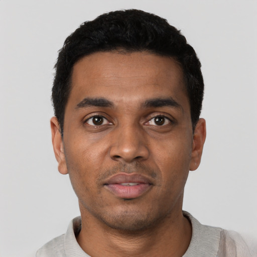 Joyful black young-adult male with short  black hair and brown eyes