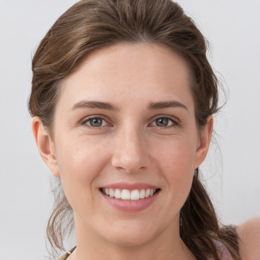 Joyful white young-adult female with medium  brown hair and grey eyes