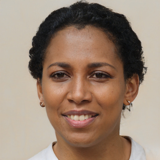 Joyful black young-adult female with short  black hair and brown eyes