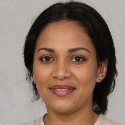 Joyful latino adult female with medium  black hair and brown eyes