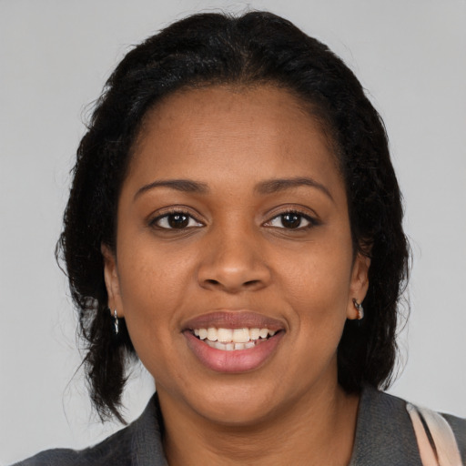 Joyful black young-adult female with long  black hair and brown eyes