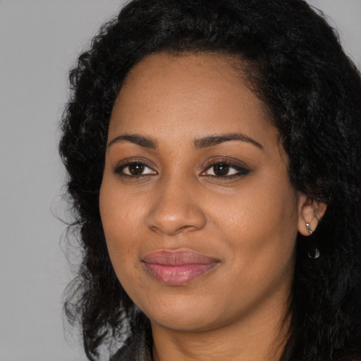 Joyful black young-adult female with long  black hair and brown eyes