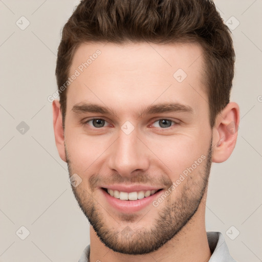 Joyful white young-adult male with short  brown hair and grey eyes