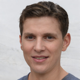 Joyful white young-adult male with short  brown hair and grey eyes