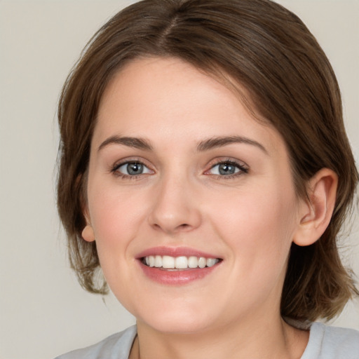 Joyful white young-adult female with medium  brown hair and green eyes