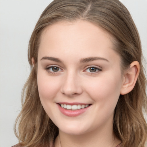 Joyful white young-adult female with long  brown hair and grey eyes