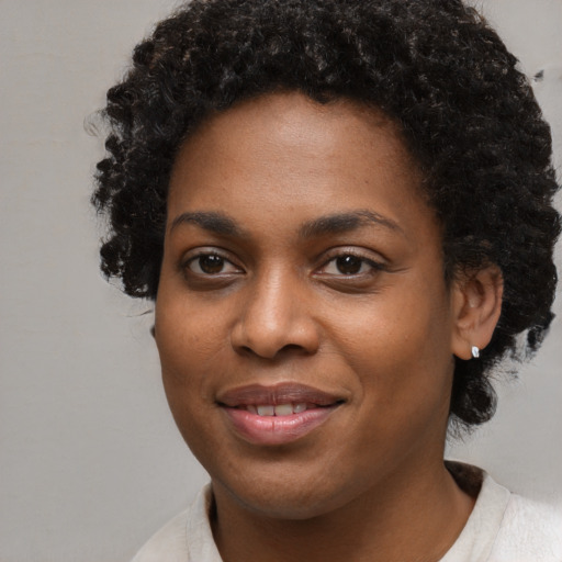 Joyful black young-adult female with short  black hair and brown eyes