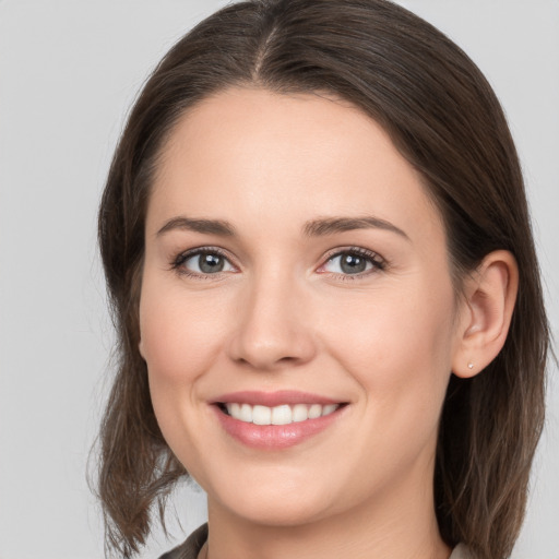 Joyful white young-adult female with medium  brown hair and grey eyes