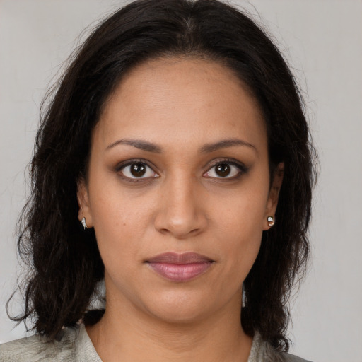 Joyful black young-adult female with long  brown hair and brown eyes