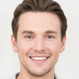 Joyful white young-adult male with short  brown hair and grey eyes