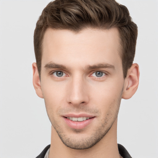 Joyful white young-adult male with short  brown hair and grey eyes