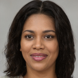 Joyful black young-adult female with long  brown hair and brown eyes