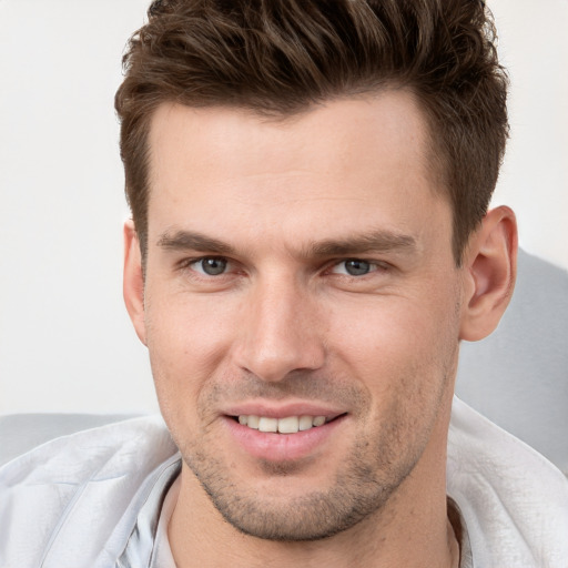 Joyful white young-adult male with short  brown hair and grey eyes