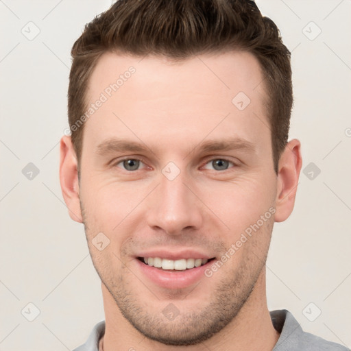 Joyful white young-adult male with short  brown hair and grey eyes