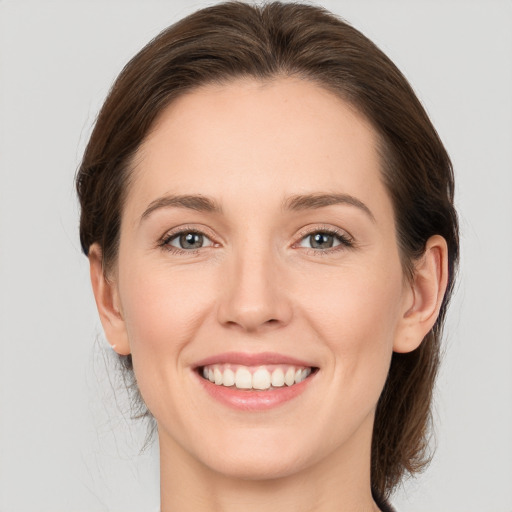 Joyful white young-adult female with medium  brown hair and grey eyes