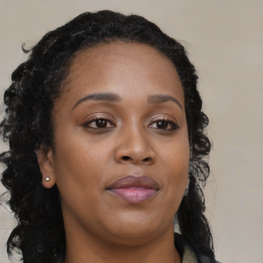 Joyful black young-adult female with long  brown hair and brown eyes