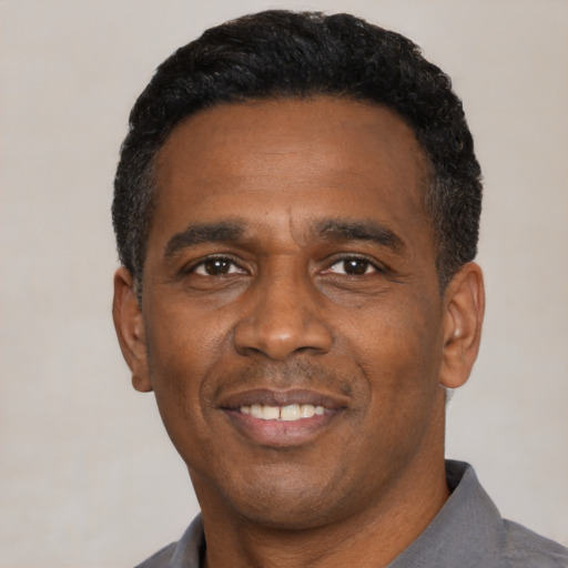 Joyful black adult male with short  black hair and brown eyes