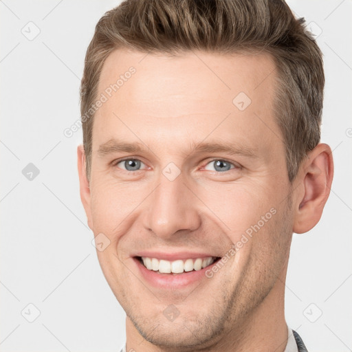 Joyful white young-adult male with short  brown hair and grey eyes