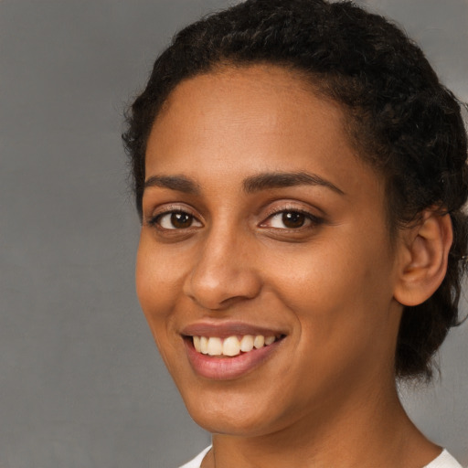 Joyful black young-adult female with short  brown hair and brown eyes