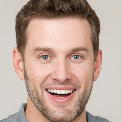 Joyful white young-adult male with short  brown hair and grey eyes