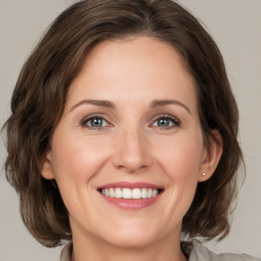 Joyful white young-adult female with medium  brown hair and grey eyes