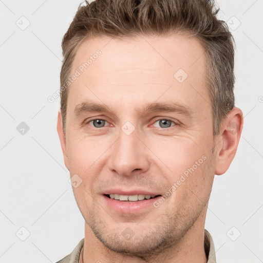 Joyful white young-adult male with short  brown hair and grey eyes