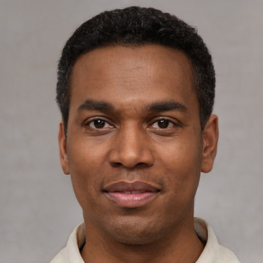 Joyful black young-adult male with short  black hair and brown eyes