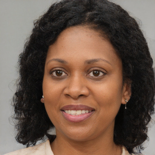 Joyful black young-adult female with long  brown hair and brown eyes