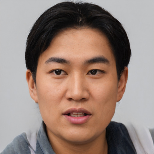 Joyful asian young-adult male with short  black hair and brown eyes