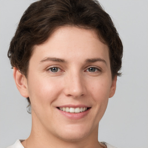 Joyful white young-adult female with short  brown hair and grey eyes