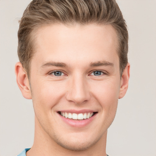 Joyful white young-adult male with short  brown hair and grey eyes