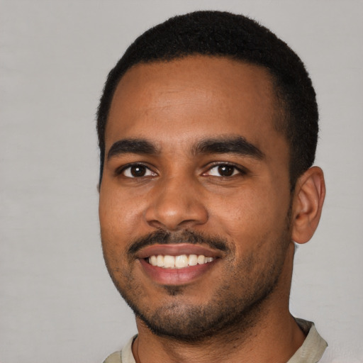 Joyful black young-adult male with short  black hair and brown eyes