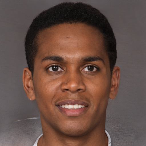 Joyful black young-adult male with short  brown hair and brown eyes