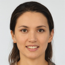 Joyful white young-adult female with long  brown hair and brown eyes