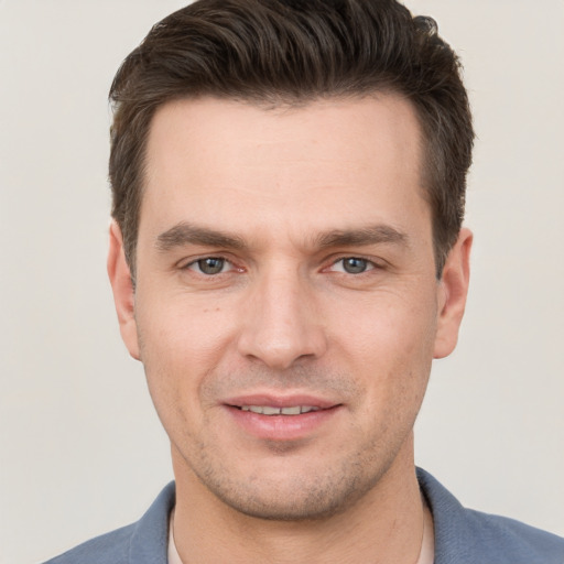 Joyful white young-adult male with short  brown hair and grey eyes