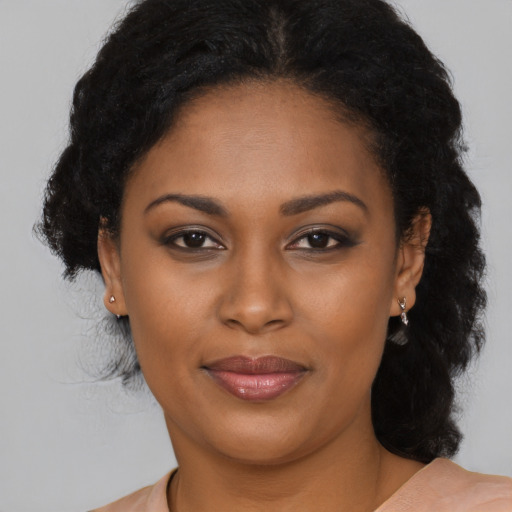 Joyful black young-adult female with long  brown hair and brown eyes