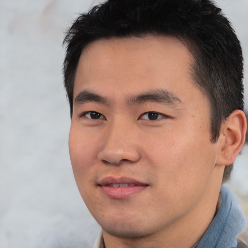 Joyful asian young-adult male with short  black hair and brown eyes