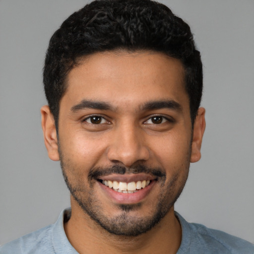 Joyful latino young-adult male with short  black hair and brown eyes